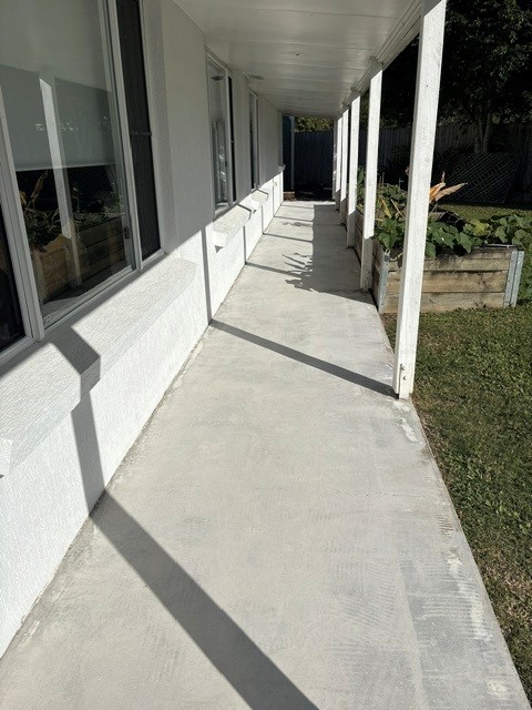 Freshly pressure washed concrete path alongside a house