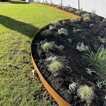 Corten steel edging curving between lawn and garden bed