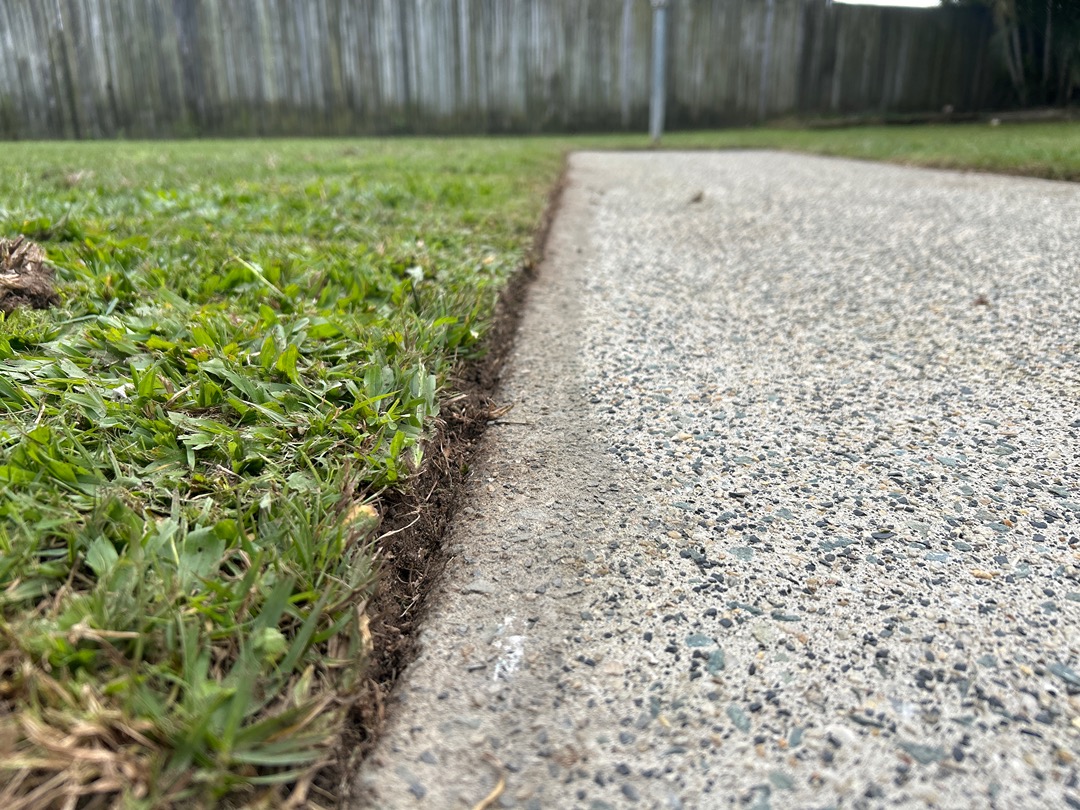 A clean edge cut between a green lawn and a concrete path